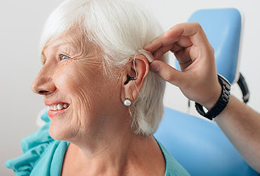 An elderly woman with hearing loss gets fitted with a hearing aid