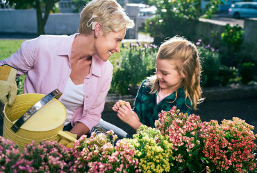 An older woman waters her garden with her granddaughter with help from her cochlear implants